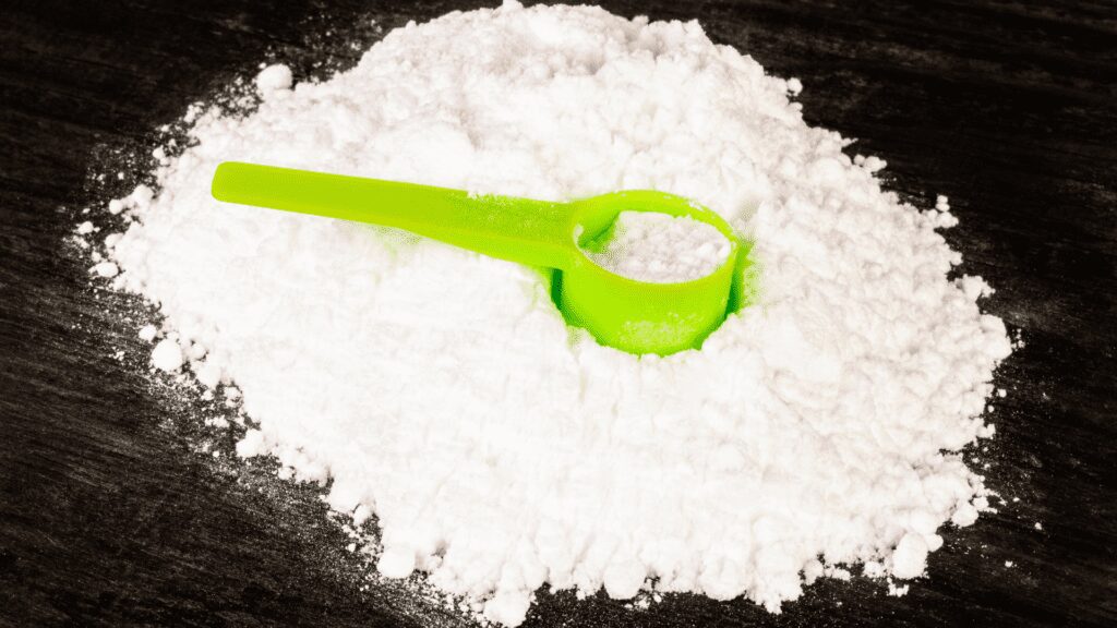 Creatine accompanied by a green plastic scoop for precise measurement