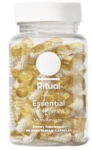 This is an image of Ritual's multivitamin bottle, sleek and cylindrical in shape. It's transparent, showcasing the yellow, bead-like vitamins inside, symbolizing its no-secrets approach to ingredients. The label is minimalist and modern, with 'Ritual' printed in bold, black letters against a clean, white background. The product promises essential nutrients for different life stages, encapsulating health and wellness.