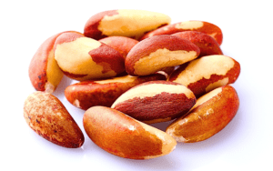 A close-up image featuring a handful of Brazil nuts against a clean white background. The nuts are characterized by their large size, smooth texture, and distinct oblong shape.