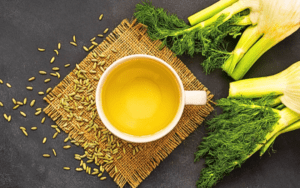 A luscious fennel bunch, delicately scattered fennel seeds, and a steaming cup of fennel tea adorning a stylish slate table.